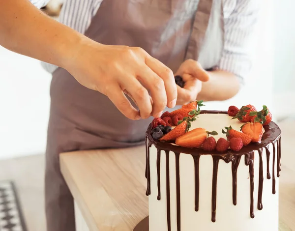 Шеф-повар украшает торт дикими ягодами — стоковое фото