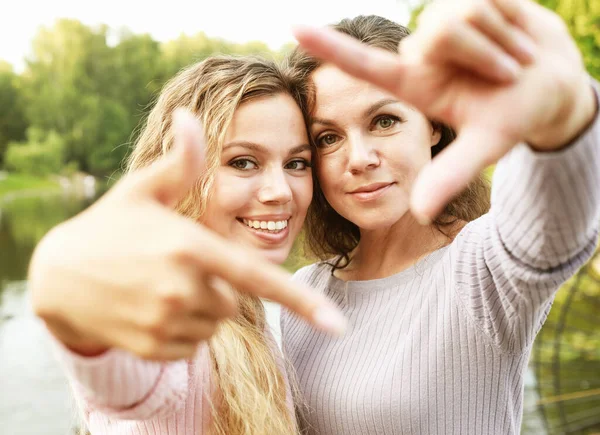 Mutter und ihre erwachsene Tochter ruhen sich im Park aus und schauen durch den Fingerrand — Stockfoto