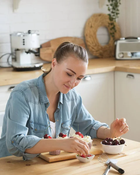 Young woman pastry chef decorates cupcakes — Stock Photo, Image