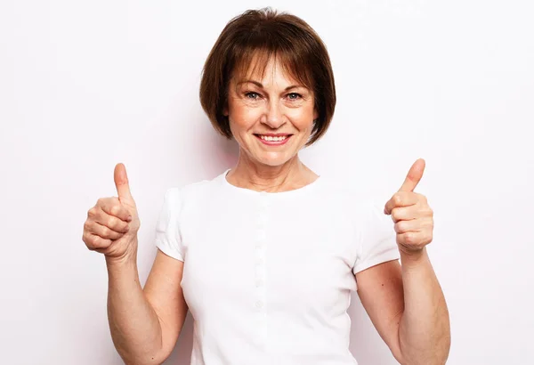 Stará šťastná žena ukazuje ok znamení přes bílé pozadí — Stock fotografie