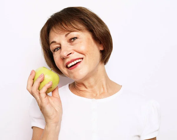 Starší usmívající se žena se zeleným jablkem přes bílé pozadí — Stock fotografie