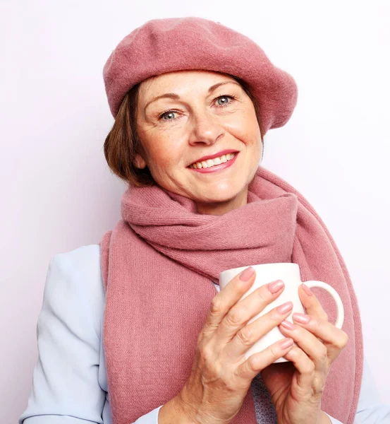 Mulher idosa alegre com sorriso bonito segurando uma xícara no fundo branco — Fotografia de Stock
