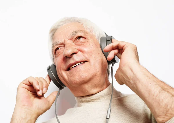 Estilo de vida, tehnología y concepto de personas: anciano escuchando música con auriculares sobre fondo blanco — Foto de Stock