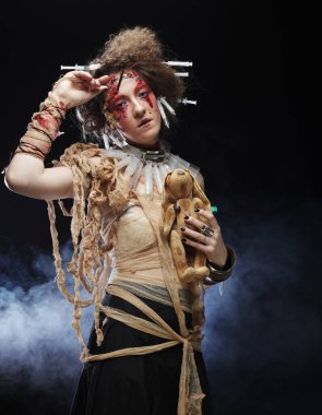 Zombi tarzı genç bir kadın elinde oyuncak bir tavşan tutuyor. Parlak makyaj ve saç stili. Parti konsepti.