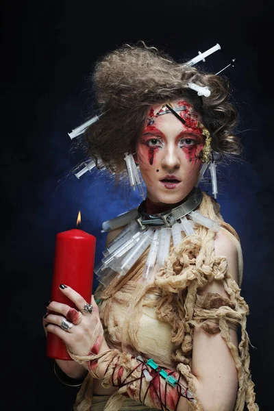 Mujer joven con maquillaje creativo y peinado sosteniendo una vela. Tema Halloween. — Foto de Stock