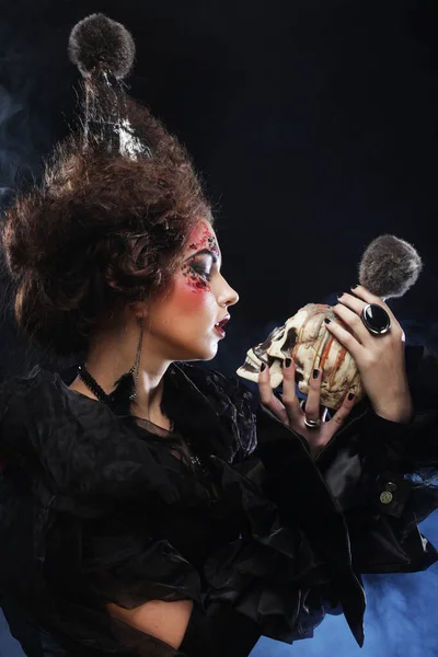 Wyobraź sobie piękną kobietę fantasy z twórczym makijażem i fryzurą trzymającą czaszkę. Motyw Halloween. Temat imprezy. — Zdjęcie stockowe