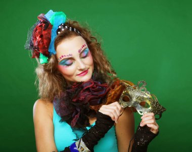 Maskeli güzel kıvırcık kadın. Karnaval çehresi. Yeşil arka planda bir kadın portresi.