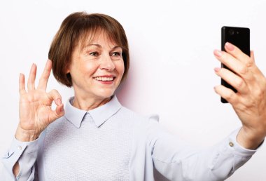 Onun portresi. Güzel, çekici, güzel, modaya uygun, neşeli, neşeli, gri saçlı, beyaz arka planda tek başına selfie çektiren bir kadın. Yaşam tarzı ve tehnoloji konsepti.