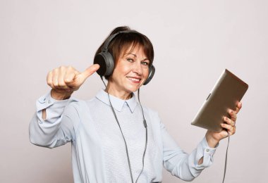 Yaşam tarzı, tehnoji ve insan konsepti: Yaşlı bir kadın tablet kullanarak yeni bir meslek edinir ve iyi olduğunu gösterir. Öğrenmeyi dinler. Geliştirme.