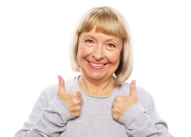 Yaşam tarzı, duygu ve insan konsepti: Yaşlı mutlu kadın başparmağını kaldırıyor ve beyaz arka plan üzerinden kameraya bakıyor