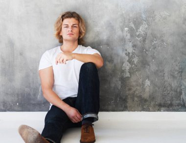 Zarif genç yakışıklı adam gri duvarın üzerinde poz veriyor. Stüdyo moda portresi. Yaşam tarzı ve insan kavramı.