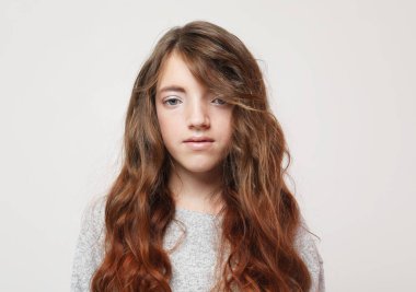 Uzun kıvırcık saçlı küçük kız, beyaz arka planda çekim yapıyor..