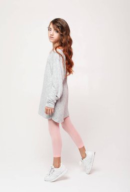 Beyaz arka planda poz veren tatlı kıvırcık kız. Yaşam tarzı ve moda konsepti.