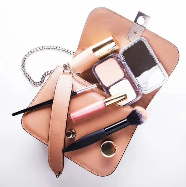 Flat lay of pink leather woman bag open out with cosmetics and accessories on white background. — Stock Photo, Image