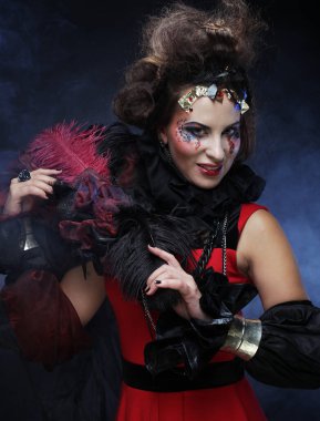 Yaratıcı makyajlı, esmer ve koyu renk arka planda saç modeli olan genç bir kadın. Parti zamanı ve cadılar bayramı.