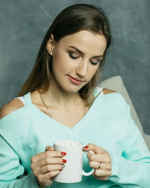漂亮又可爱漂亮的年轻女子手里拿着咖啡杯 坐在家里的椅子上 生活方式和人的概念 — 图库照片