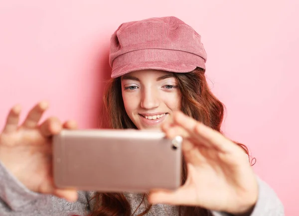 ライフスタイル テクノロジー 人々の概念 ピンクの背景に隔離された自撮り帽子をかぶった陽気な女の子の肖像 — ストック写真