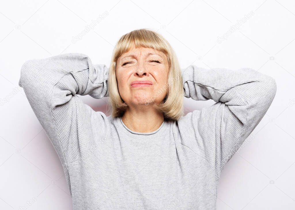 Lifestyle, health and old people concept: Beautiful mature woman touching her head having a headache, on white background
