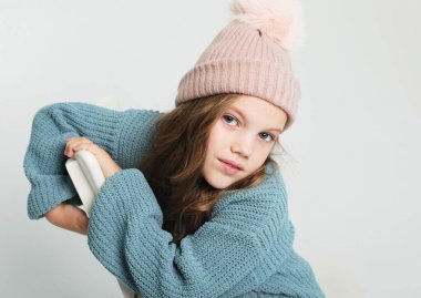 Sarı dalgalı saçlı ve kış şapkalı, gülümseyen bir çocuğun portresi. Mutlu güzel kız kameraya bak ve gülümse. Kapat..