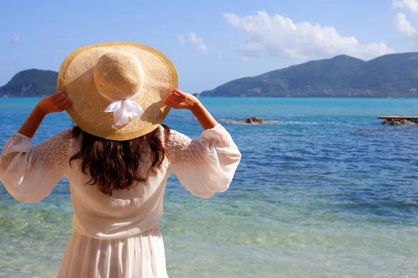 空と海を探してわら帽子と夏の白いドレスの若い女性 バックビュー — ストック写真