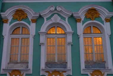 Rusya, Saint Petersburg 'daki Winter Palace binasının süslemeli tarihi pencereleri. Üç güzel dekoratif pencere, tarihi Winter Palace mimarisinin eski klasik dış unsurları.