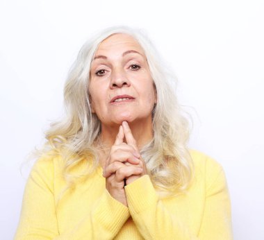 Duygu, yaşam tarzı ve yaşlı insan konsepti: Yüzünde kırışıklıklar olan mutlu yaşlı kadın beyaz arka plan üzerine sarı kazak giyiyor