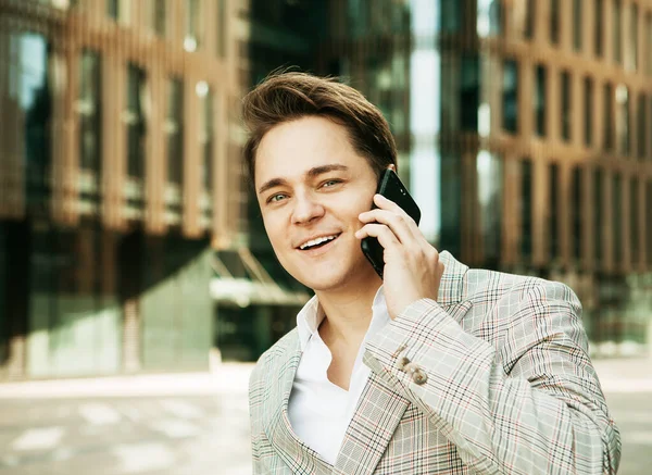 Business, people, tehnology and lifestyle concept: Young handsome businessman talking on his phone outdoors