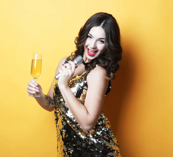 Concepto de fiesta y gente: Joven mujer de lujo con vestido de noche sosteniendo una copa de champán y micrófono. — Foto de Stock