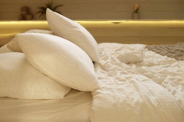 Yatak odasında yatak, beyaz yastıklar ve rahat çarşaflar.