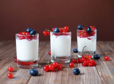 İyi sabahlar. Sağlıklı kahvaltı - beyaz yoğurt, cam kavanozda taze böğürtlen, ahşap arka planda.