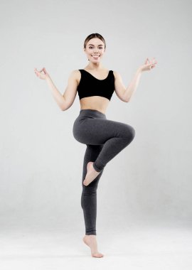 Spor giyimli güzel bir kadının portresi stüdyoda çalışıyor. Formda kız yoga yapıyor. Tam boy. Beyaz arkaplan.