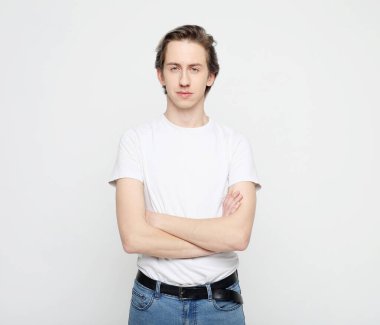 Yaşam tarzı, duygu ve insan konsepti: yakışıklı genç adam beyaz arka planda kameraya bakan beyaz tişört giyiyor