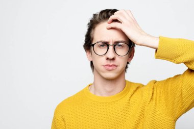 Yaşam tarzı ve vücut dili kavramı: baş ağrısından muzdarip sarı süveter giyen yakışıklı genç adam. Yorgunluk, depresyon, migren..