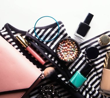 Kozmetik ürünleri, aksesuarlar ve beyaz arka planda akıllı telefonlu pembe deri kadın çantası.