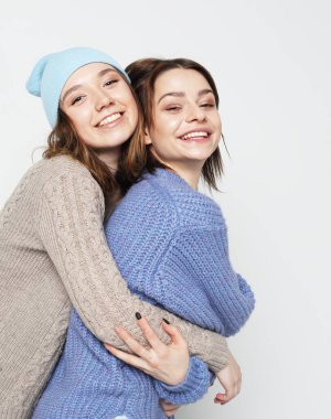 Yaşam tarzı, insanlar ve arkadaşlık kavramı: İki genç bayan arkadaş bir arada duruyor ve beyaz arka planda eğleniyorlar