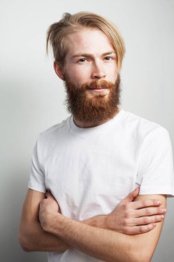 Beyaz arka planda doğal sarışın beyaz adamın portresi. Sakallı hippi sakallı, sakalları tıraşlı ve şık bıyıklı. Ciddi ve vahşi görünüyor..