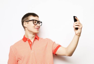 Beyaz arka plan, yaşam tarzı ve insan konsepti üzerinden kendi portresini çeken yakışıklı beyaz adam.