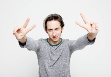 Mutlu tesadüfi adam beyaz arka planda zafer ya da barış işareti yapıyor.