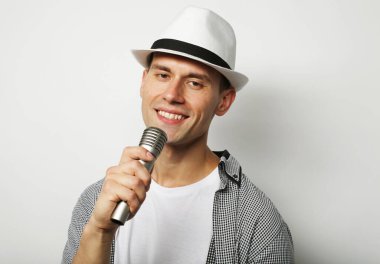 Beyaz arka planda izole edilmiş, elinde mikrofon tutan konuşan genç bir adam..