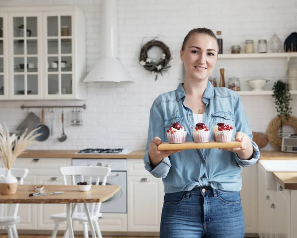 Genç fırıncı kadın elinde kek tutuyor..