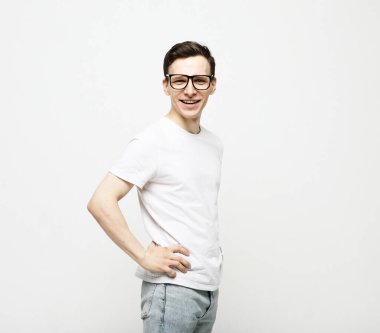 Beyaz arka planda beyaz tişört ve gözlük takan genç adam.