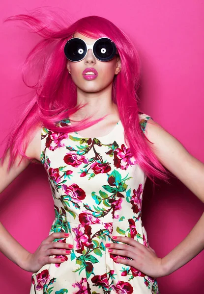 Fashion and beauty concept: fashion girl with pink hair and big sunglasses over pink background