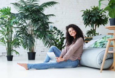 Güzel Afro-Amerikan kadın yerde otururken dijital tablet kullanıyor. Yaşam tarzı, eğitim ve insan kavramı.