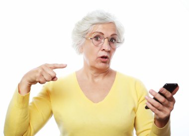 Heyecan verici bir haber. Yaşlı bir kadın haberi duydu ve parmağıyla telefonu işaret ederek dikkat çekti. Fotoğraf beyaz arkaplan üzerinde.