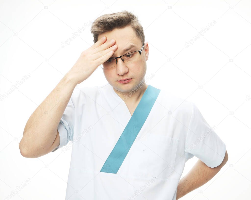 Medicine COVID-19 concept. Handsome doctor man wearing medical uniform over white background tired rubbing forehead, feeling fatigue and headache. Stress and frustration.