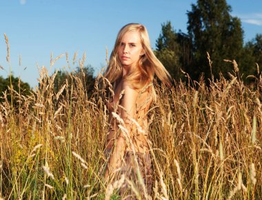 Güzel, genç bir bayan model. Sarı saçlı. Bir yaz günü çıplak poz veriyor..