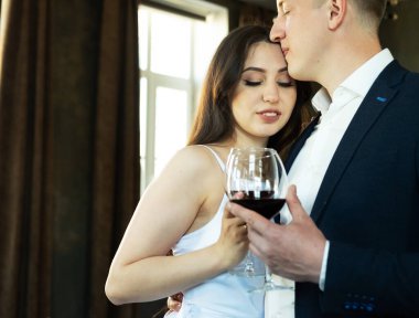 Genç evli çift şarap içip mutluluklarına, romantizmlerine ve şefkatlerine gülümsüyor.