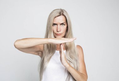 Jest, içki yasağı ve yaşlı insan konsepti: Gri arkaplan üzerinde mola veren uzun gri saçlı yaşlı kadın.