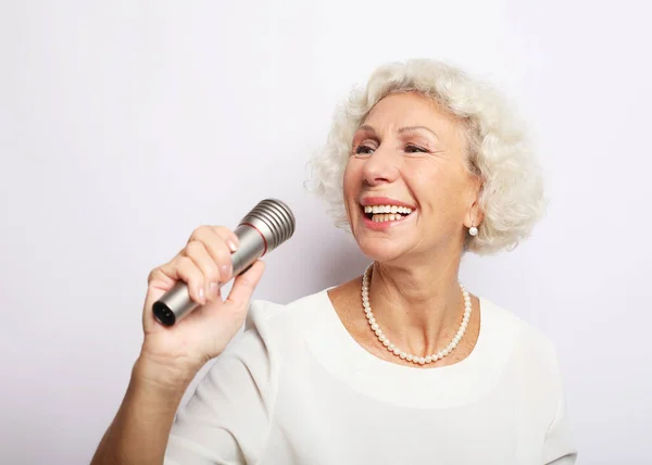 Emotion, lifestyle and old people concept: Happy senior woman singing with microphone, having fun, expressing musical talent