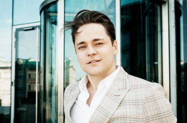 Genç bir iş adamının portresi, yakın plan, modern bir ofisin yanında duran bir adam.